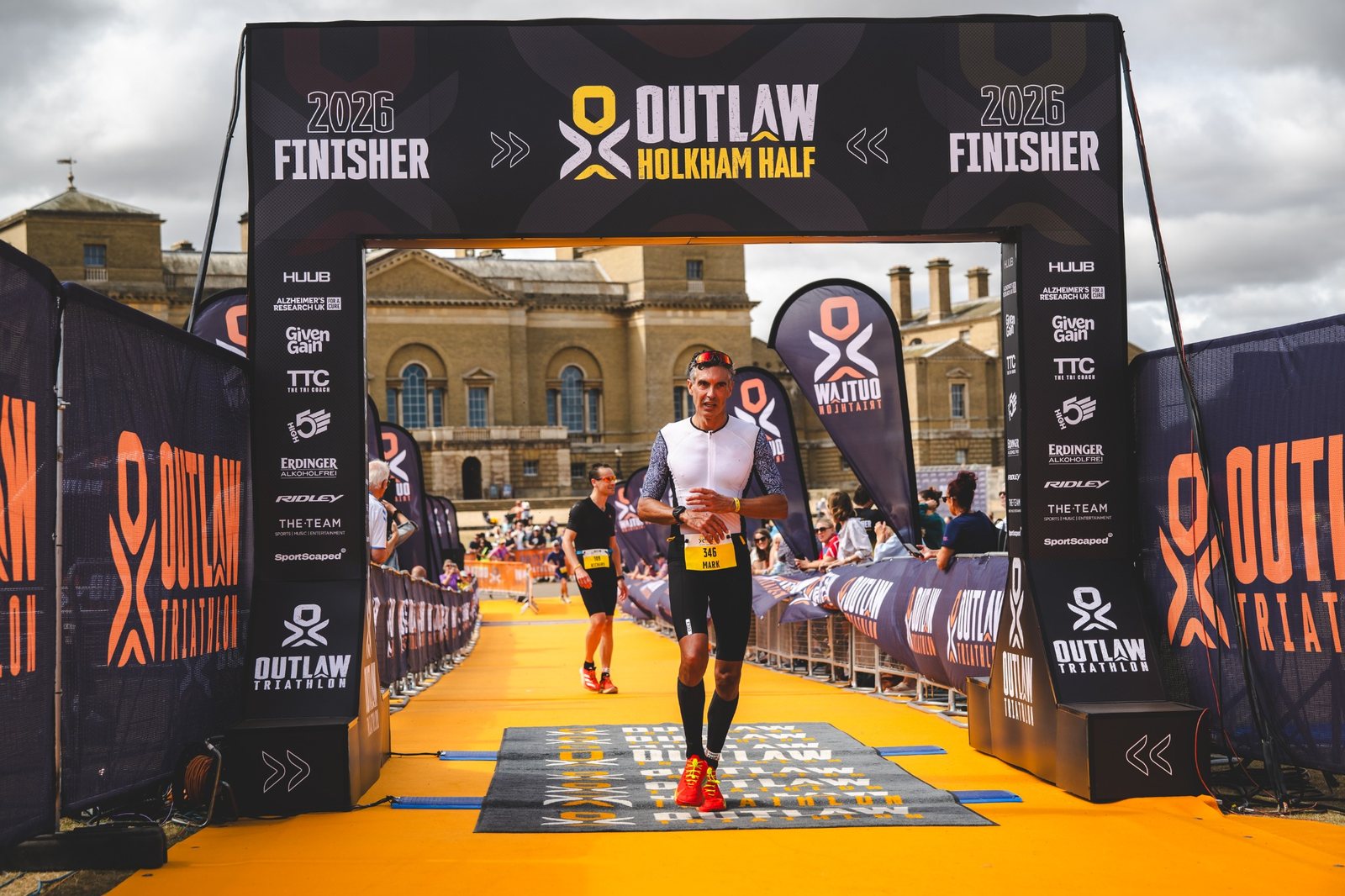 Mark Ash crossing the finish line at Outlaw Holkham Half